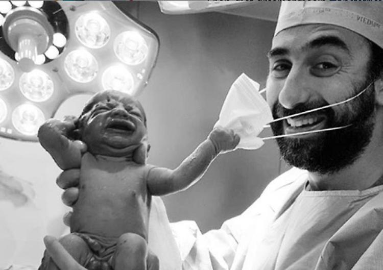 Foto della speranza, neonato strappa la mascherina al medico